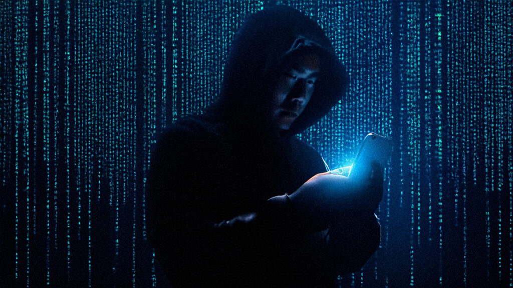 Person in a dark hoodie using a smartphone, symbolising Pegasus spyware surveillance in Europe