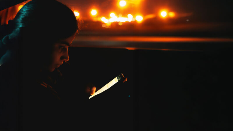 A young woman, deeply consumed by her phone, symbolising the addictive nature of the Instagram algorithm. Image from Unspalsh, credits in the references