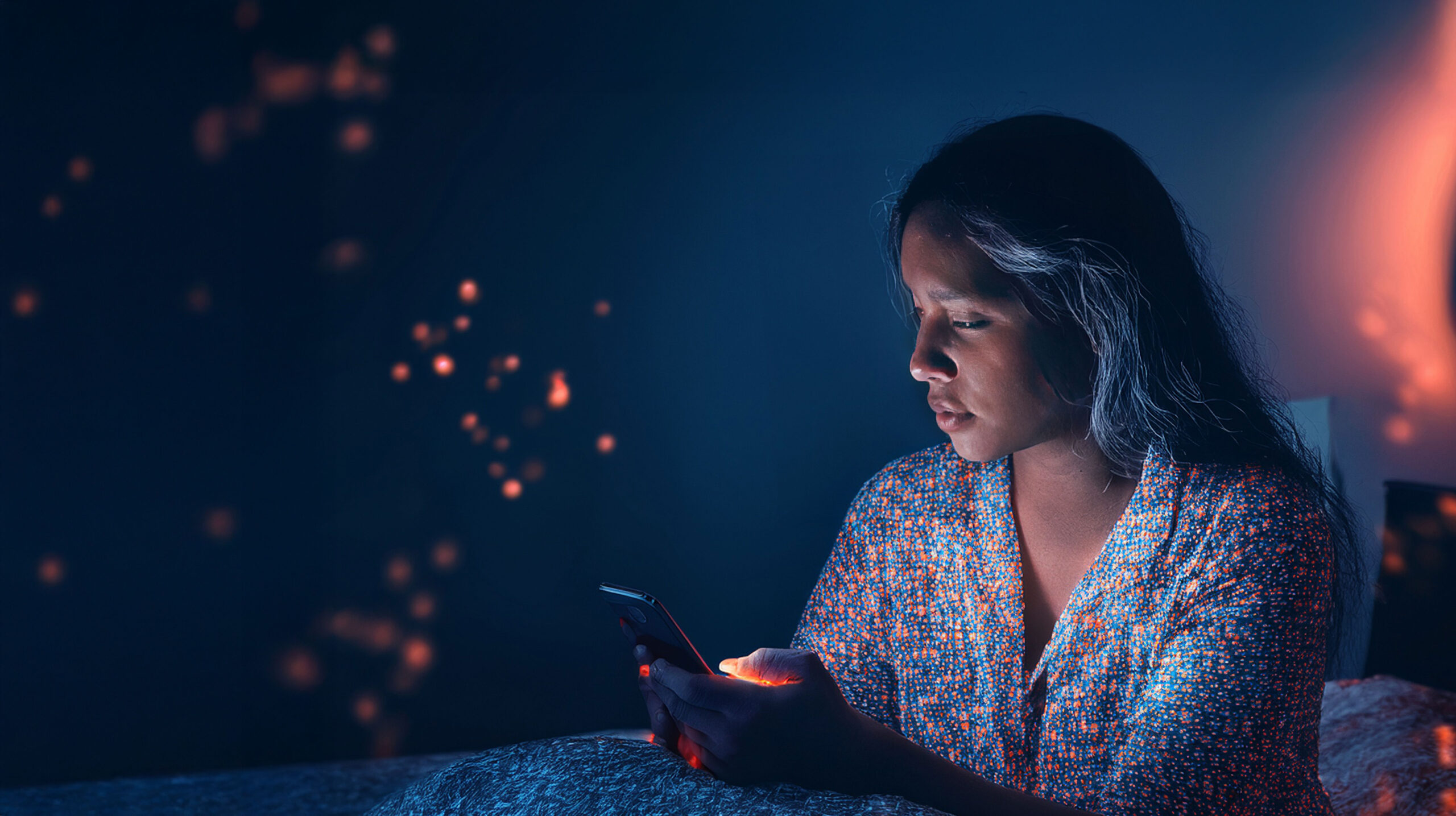 A person using a smartphone at night, representing emotional vulnerability and the human impact of online romance scams linked to so-called “Yahoo Boys”.